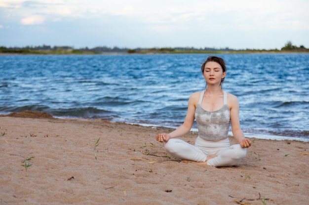 Kobieta uprawiająca jogę na zewnątrz w pozie lotosu na plaży