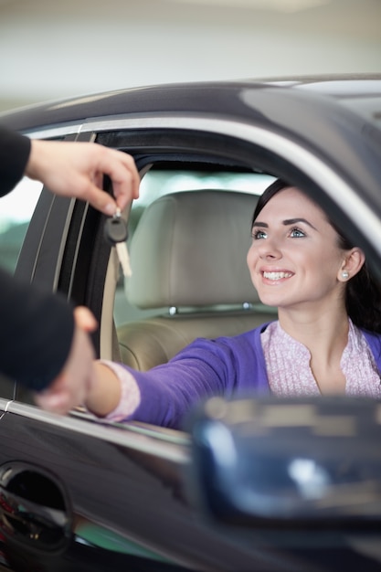 Kobieta uśmiechając się w samochodzie, wstrząsając ręcznie