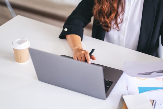 Kobieta używa i pracuje na laptopie i papierkowej roboty w biurze