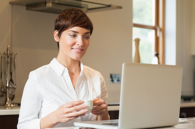 Kobieta używa laptop i pijący kawę