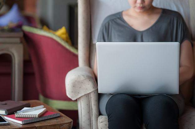 Kobieta używa laptop w domu obok okno