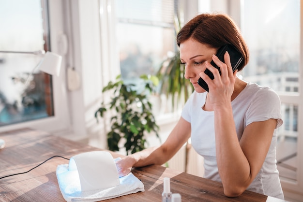 Kobieta używa mądrze telefon podczas gdy suszący gwoździe