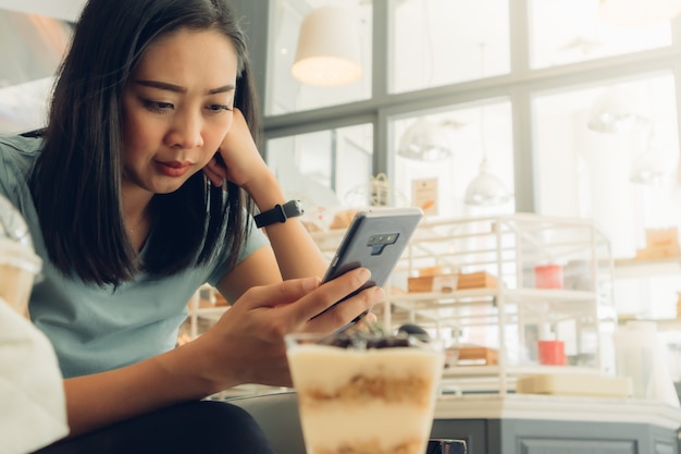 Kobieta używa smartphone w piekarni kawiarni.
