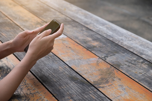 Kobieta używa telefon komórkowego na drewnianych deskach