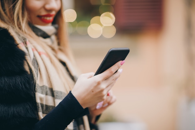 Kobieta używa telefon komórkowego w zimnej pogodzie outside w miastowych ulicach