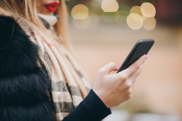 Kobieta używa telefon komórkowego w zimnej pogodzie outside w miastowych ulicach