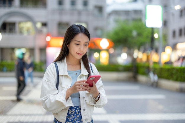 Kobieta używa telefonu komórkowego w mieście w nocy