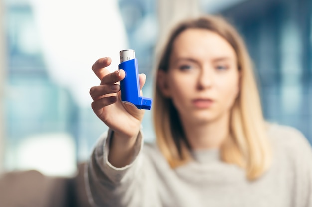 kobieta używająca inhalatora podczas astmy w domu;
