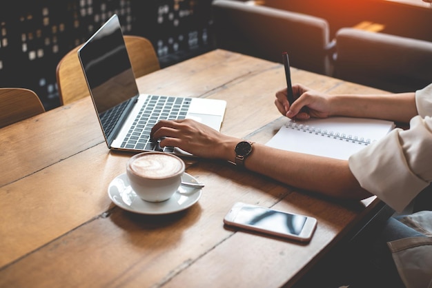 Kobieta używająca laptopa z filiżanką kawy na stole