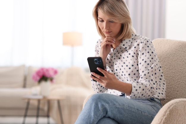 Kobieta używająca telefonu komórkowego w domu do wysyłania wiadomości.