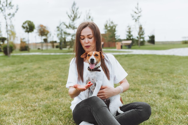 Kobieta W Białej Koszulce I Dżinsach Przytula Swojego Psa Jack Russell Terrier W Naturze W Parku Lojalni Najlepsi Przyjaciele Od Dzieciństwa Styl życia