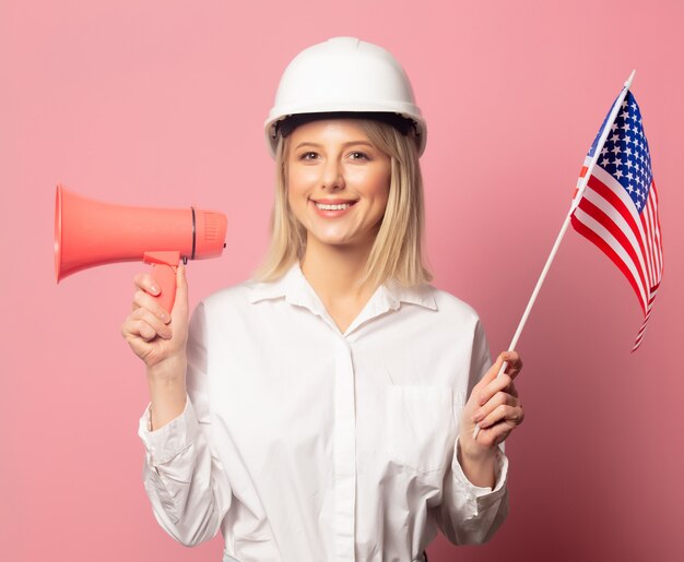 Kobieta w białej koszuli i kasku posiada głośnik i flagę USA