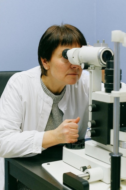 Kobieta w białej koszuli używająca białego mikroskopu