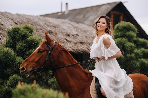 Kobieta w białej sukience na koniu w pobliżu farmy