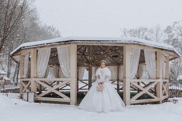 Kobieta w białej sukience stoi przed pawilonem w śniegu