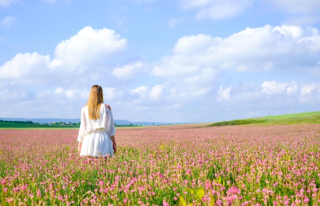 Zdjęcie kobieta w białej sukni na ukwieconym polu esparceta kobieta na kwitnącym polu różu