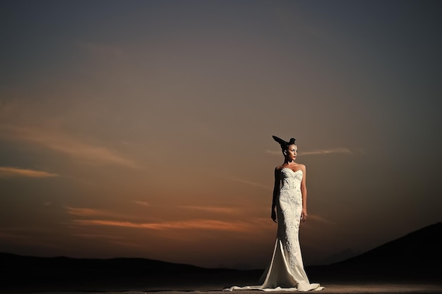 Kobieta w białej sukni ślubnej o zachodzie słońca