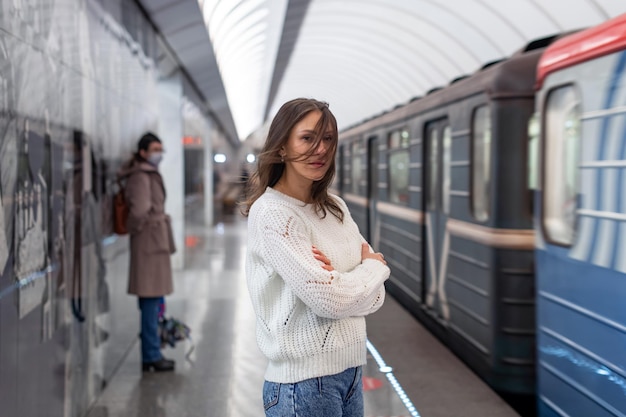 Zdjęcie kobieta w białym swetrze czekająca na pociąg na stacji metra