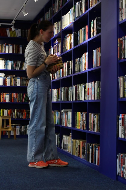 Kobieta w bibliotece w poszukiwaniu książki koncepcja edukacji odwiedza czytelnię