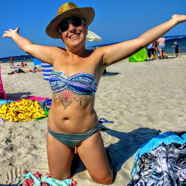 Kobieta w bikini z wyciągniętymi ramionami na plaży