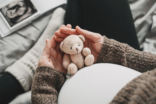 Kobieta w ciąży brzuch z małym pluszowym misiem Przyszła mama podczas ciąży