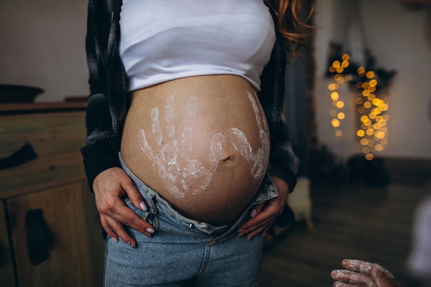 Kobieta w ciąży brzuch z nadrukami dziecka w koszuli i niebieskich dżinsach