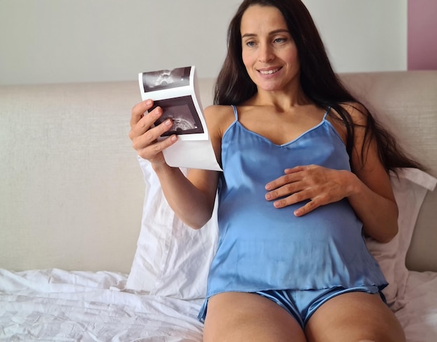 Kobieta w ciąży cieszy się przyszłym macierzyństwem z pierwszym zdjęciem USG dziecka