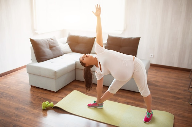 Kobieta W Ciąży ćwiczy W Domu Na Macie Do Jogi. Ciąża I Sport. Oga I Pilates Dla Kobiet W Ciąży. Trzeci Trymestr Ciąży.