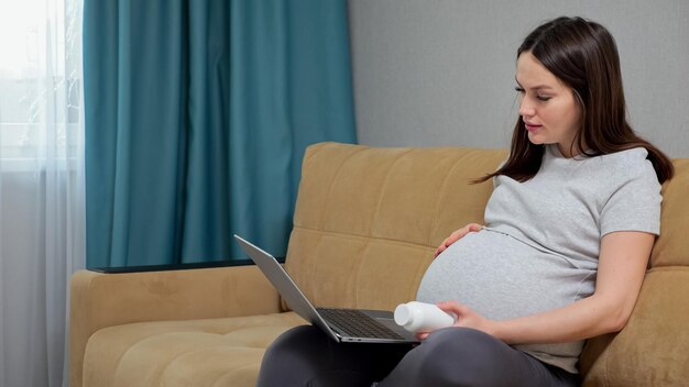 Kobieta w ciąży czyta receptę pigułki na laptopie