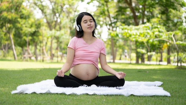 Kobieta w ciąży dotykająca brzucha w parku miejskim Ciąża Relaks i ćwiczenia Piękny, czuły nastrój zdjęcie ciąży