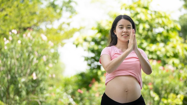 Kobieta w ciąży dotykająca brzucha w parku miejskim Ciąża Relaks i ćwiczenia Piękny, czuły nastrój zdjęcie ciąży