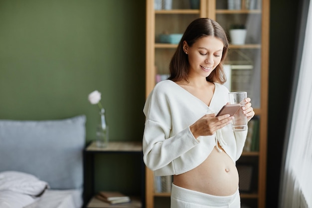 Kobieta w ciąży korzystająca z telefonu komórkowego w domu