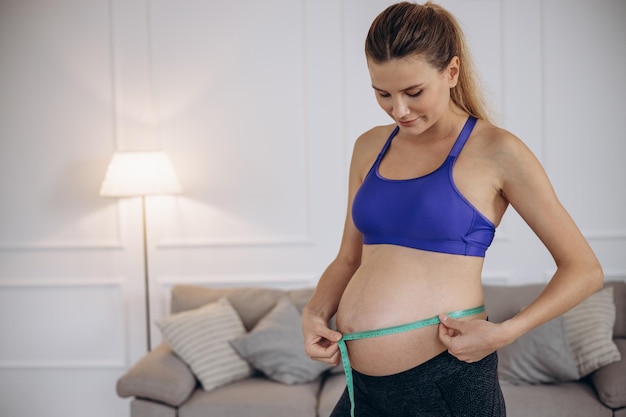 Kobieta w ciąży mierząca brzuch za pomocą taśmy mierniczej