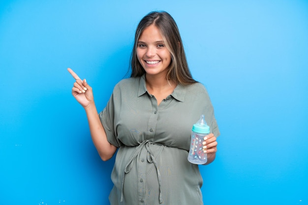 Kobieta w ciąży na niebieskim tle wskazuje na bok, aby zaprezentować produkt
