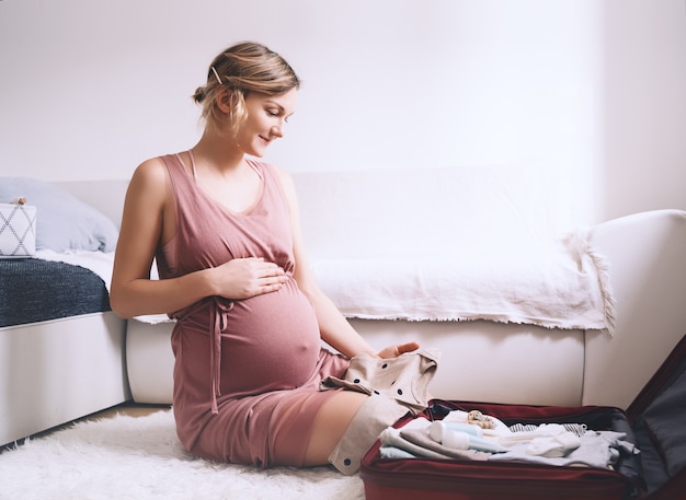 Kobieta W Ciąży Pakuje Walizkę Do Szpitala Położniczego, Przygotowując Się Do Porodu