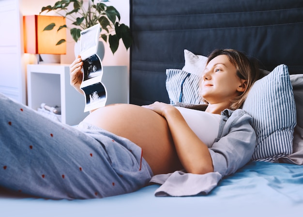 Kobieta W Ciąży Patrząca Na Obraz Usg Relaksuje Się W łóżku We Wnętrzu Domu