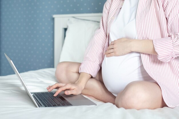 Kobieta w ciąży pracuje na laptopie.