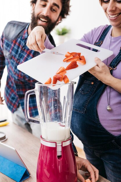 Kobieta w ciąży przygotowuje smoothie ze świeżymi truskawkami, częściowy widok