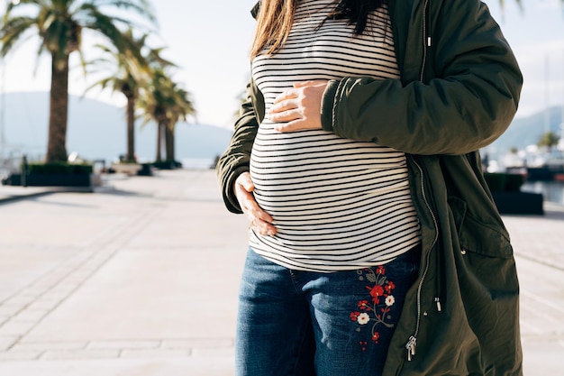 Zdjęcie kobieta w ciąży przytula brzuch rękami, stojąc na zbliżeniu nasypu