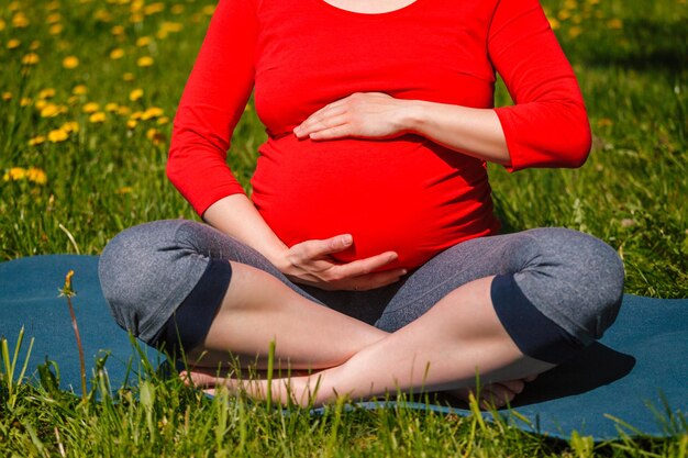 Kobieta w ciąży robi asana sukhasana na zewnątrz