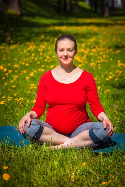 Kobieta w ciąży robi asana sukhasana na zewnątrz