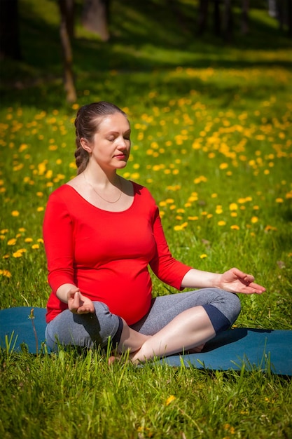 Kobieta w ciąży robi asana sukhasana na zewnątrz