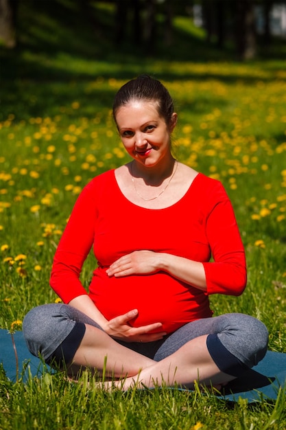 Kobieta w ciąży robi asana sukhasana na zewnątrz