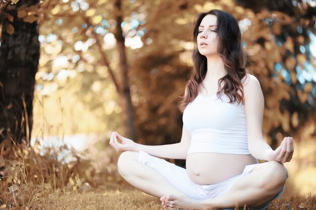 Kobieta w ciąży robi ćwiczenia jogi jesienią