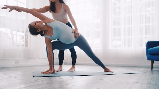 Zdjęcie kobieta w ciąży robi ćwiczenia pilates z osobistym trenerem w domu.