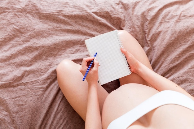 Kobieta w ciąży robi notatki w notatniku Pojęcie ciąży Matka czekająca na dziecko