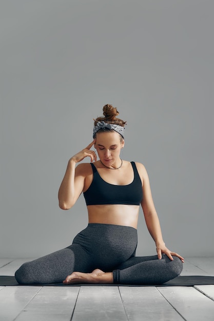 Kobieta w ciąży rozciągająca ręce i nogi podczas treningu prenatalnego w domu na macie do jogi Selektywne skupienie