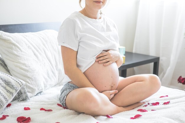 Kobieta w ciąży siedzi na łóżku trzymając Pojęcie macierzyństwa ciąży i opieki prenatalnej Mama z nowym życiem