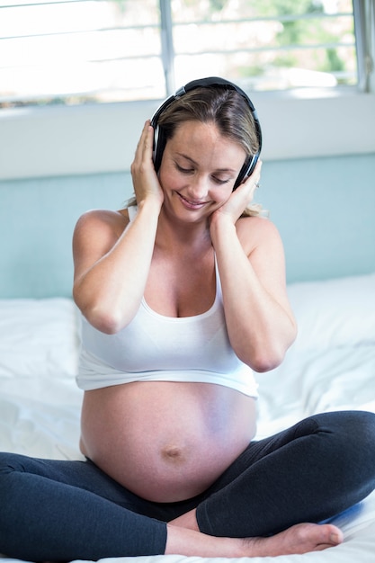 Kobieta w ciąży słucha muzyki na jej łóżku