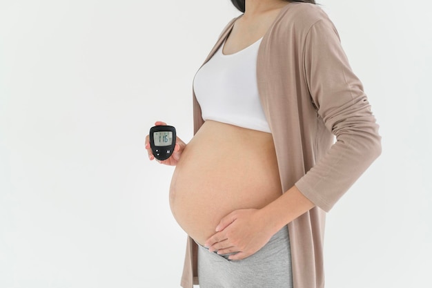 Kobieta w ciąży sprawdza poziom cukru we krwi za pomocą cyfrowego miernika glukozy